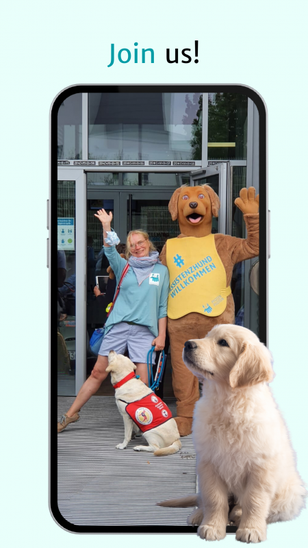 A smartphone screenshot showing a cheerful scene with a woman, a person in a dog costume and two dogs. The woman, wearing a light blue blouse and shorts, smiles and raises her hand in greeting. Next to her is a person in a golden dog costume with a sign saying '#AssistenzhundWillkommen'. An assistance Labrador and a young golden retriever look on attentively. Text at the top of the screen reads 'Join in!